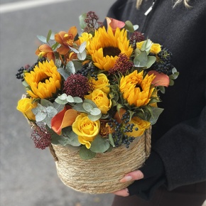 Композиция в сумке "Тональность" из подсолнухов, калл, ягод вибирнума, лимонных роз, скиммии и орхидеи в Пущино